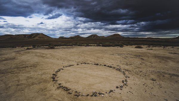 Bardenas desert photography, stone circle landscape art, dramatic storm clouds print, Spanish desert fine art, minimalist nature photography, atmospheric landscape photo, exclusive art print, limited edition desert artwork, fine art stormy skies, rustic desert scene, moody fine art decor, Spain landscape photography, collector’s fine art print, earth tones artwork, nature-inspired wall decor, cinematic desert photo, luxury landscape print, mysterious stone circle, barren landscape photo, art for luxury homes